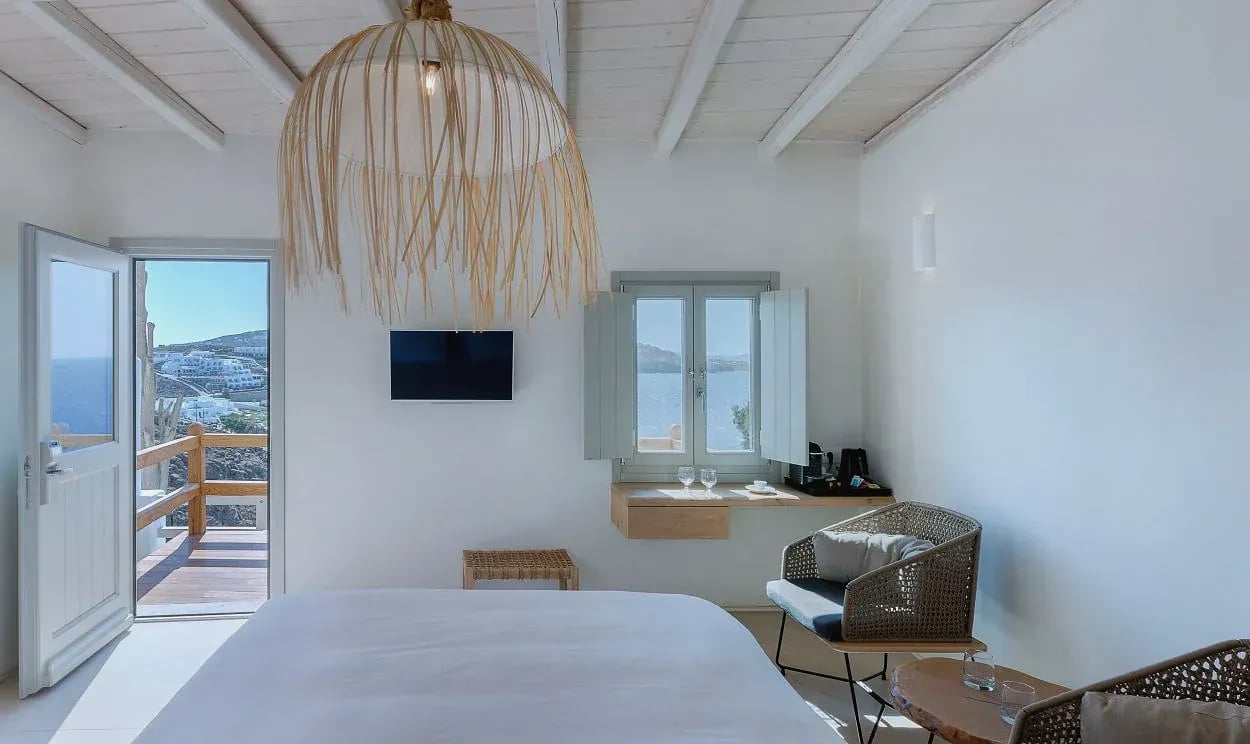 Bedroom of the Deluxe Suite Room with the balcony door open to the sea