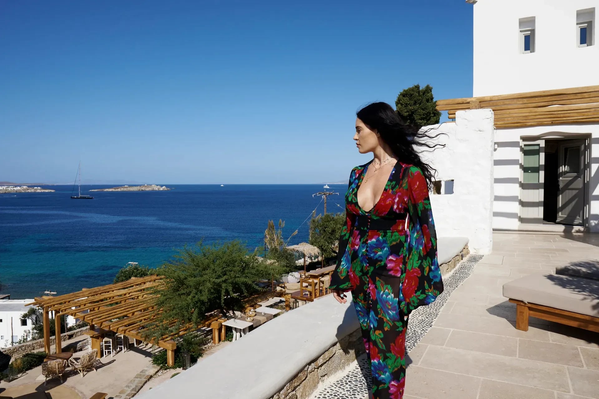 A guest walking the whitewashed path between the suites, the bay open behind her