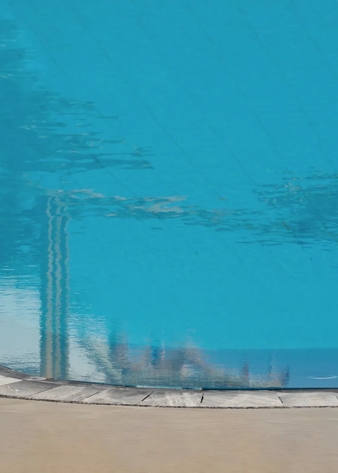 The turquoise surface of the small garden pool against its stone coping