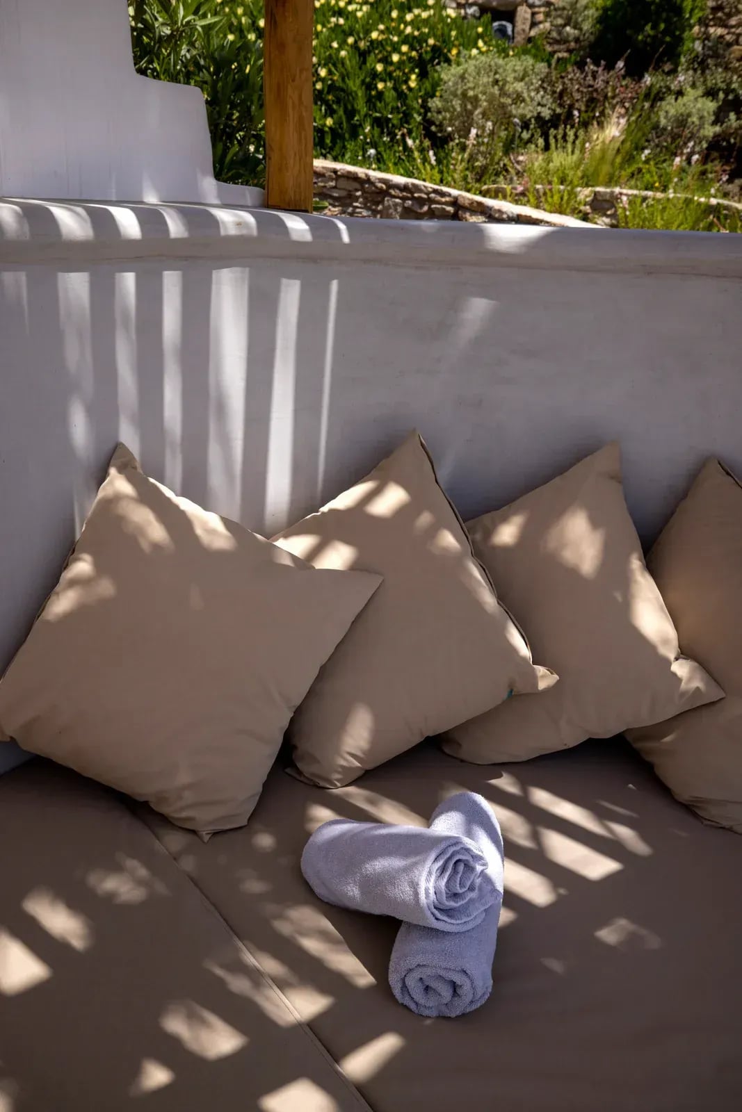 Cushions and rolled towels on a shaded terrace daybed