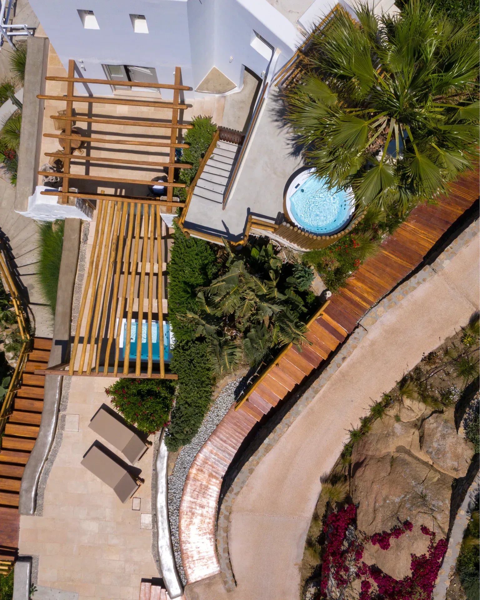 Timber sun decks and planting seen from above, between palms and bougainvillea
