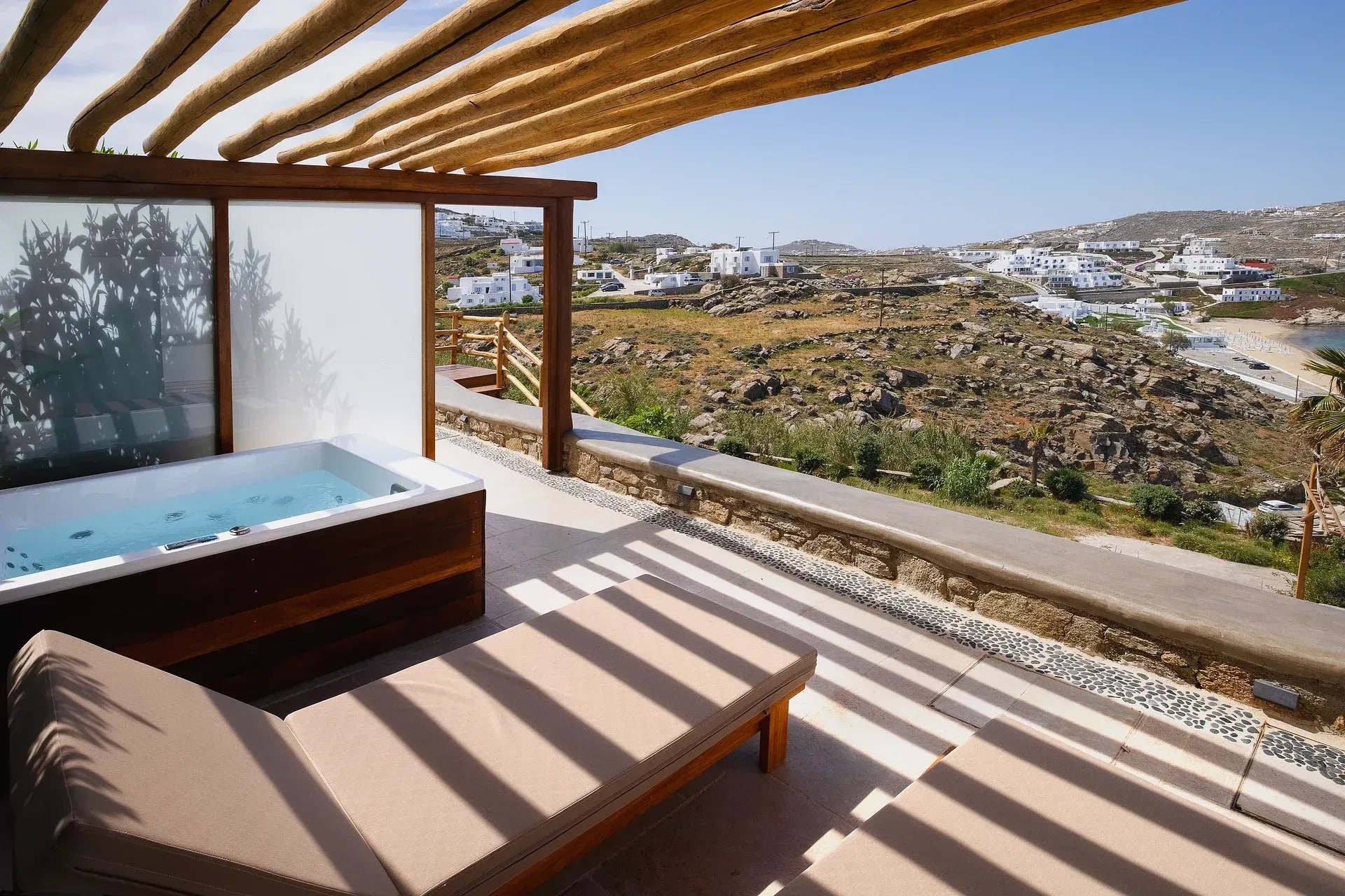 Shaded terrace with seating above the coastline at Legacy Mykonos