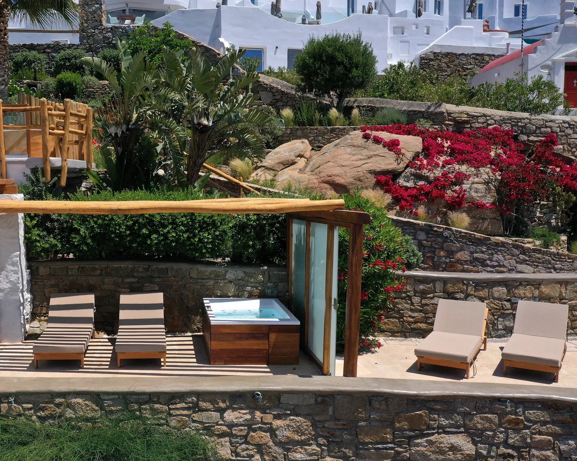 The Junior Suite terrace on the stone levels, with sun loungers, an outdoor hot tub and bougainvillea above