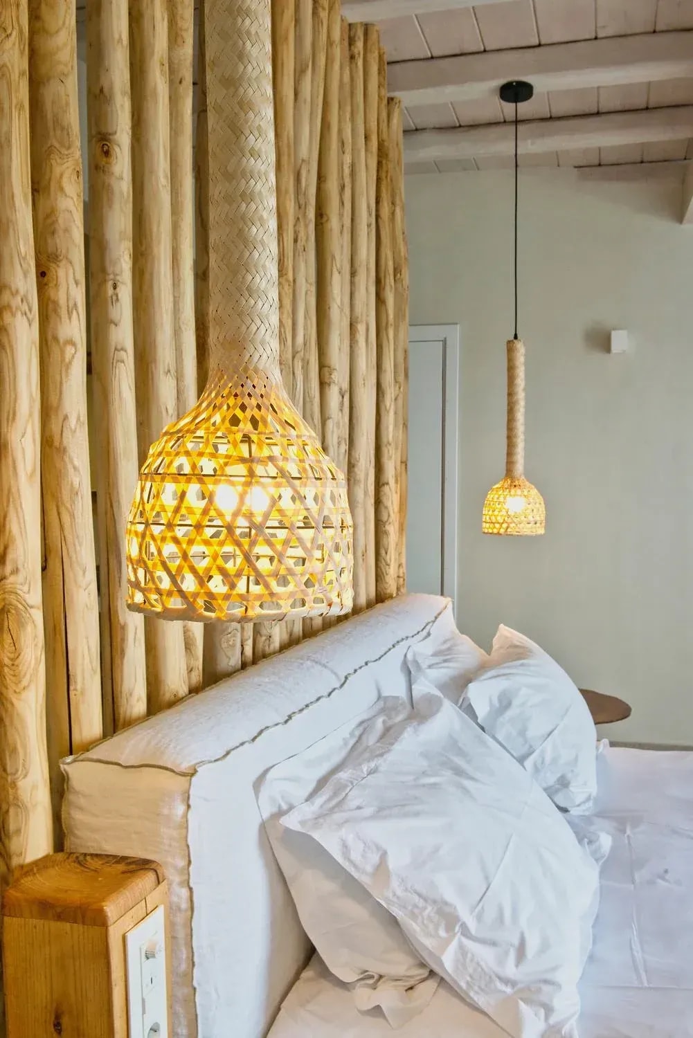 Woven pendant lamp and driftwood detail above the bed