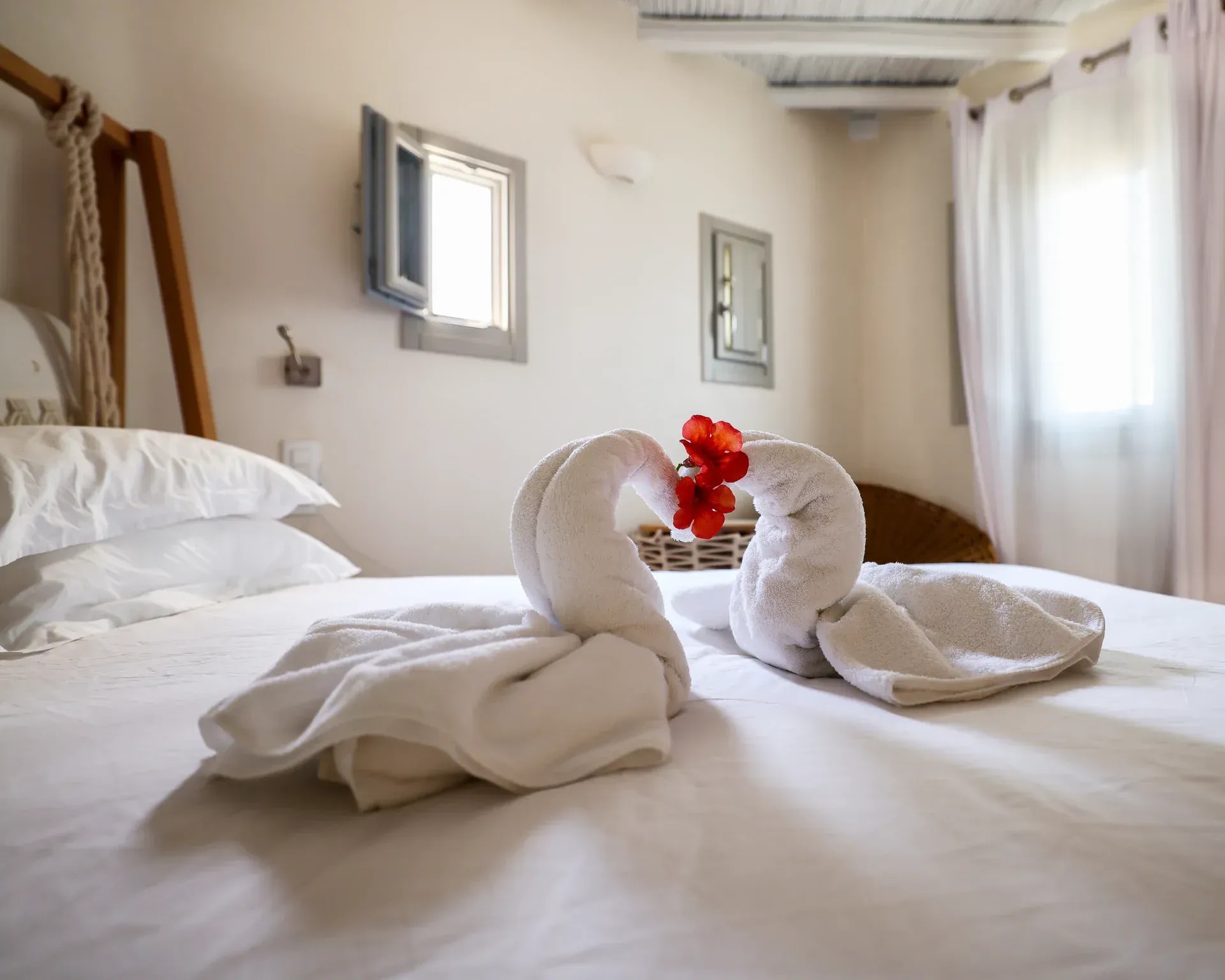 Evening turndown in a Legacy Mykonos suite, with folded towels and a flower