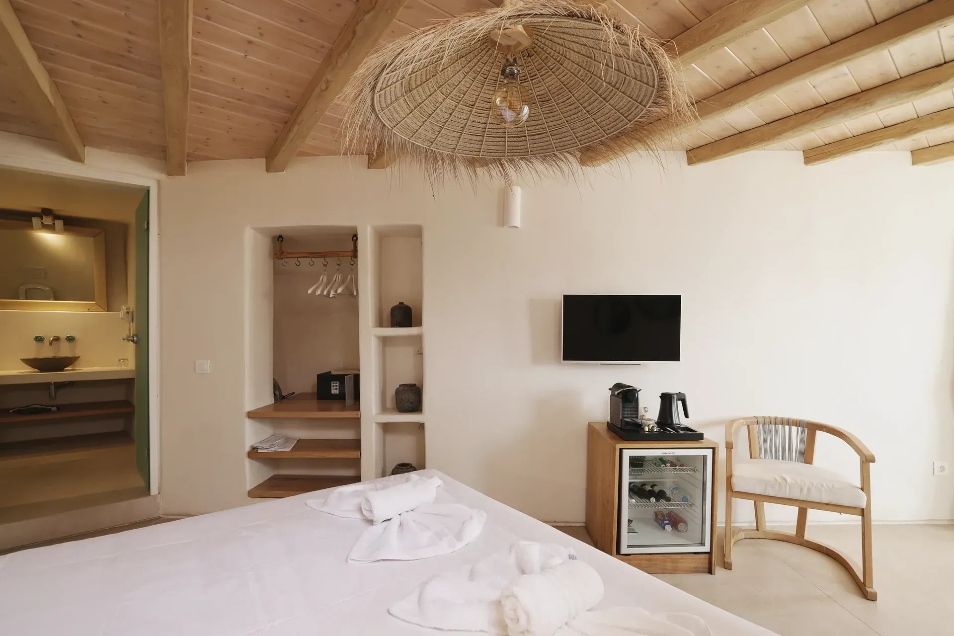 Bedroom with raw timber ceiling, straw pendant light and built-in plaster shelving