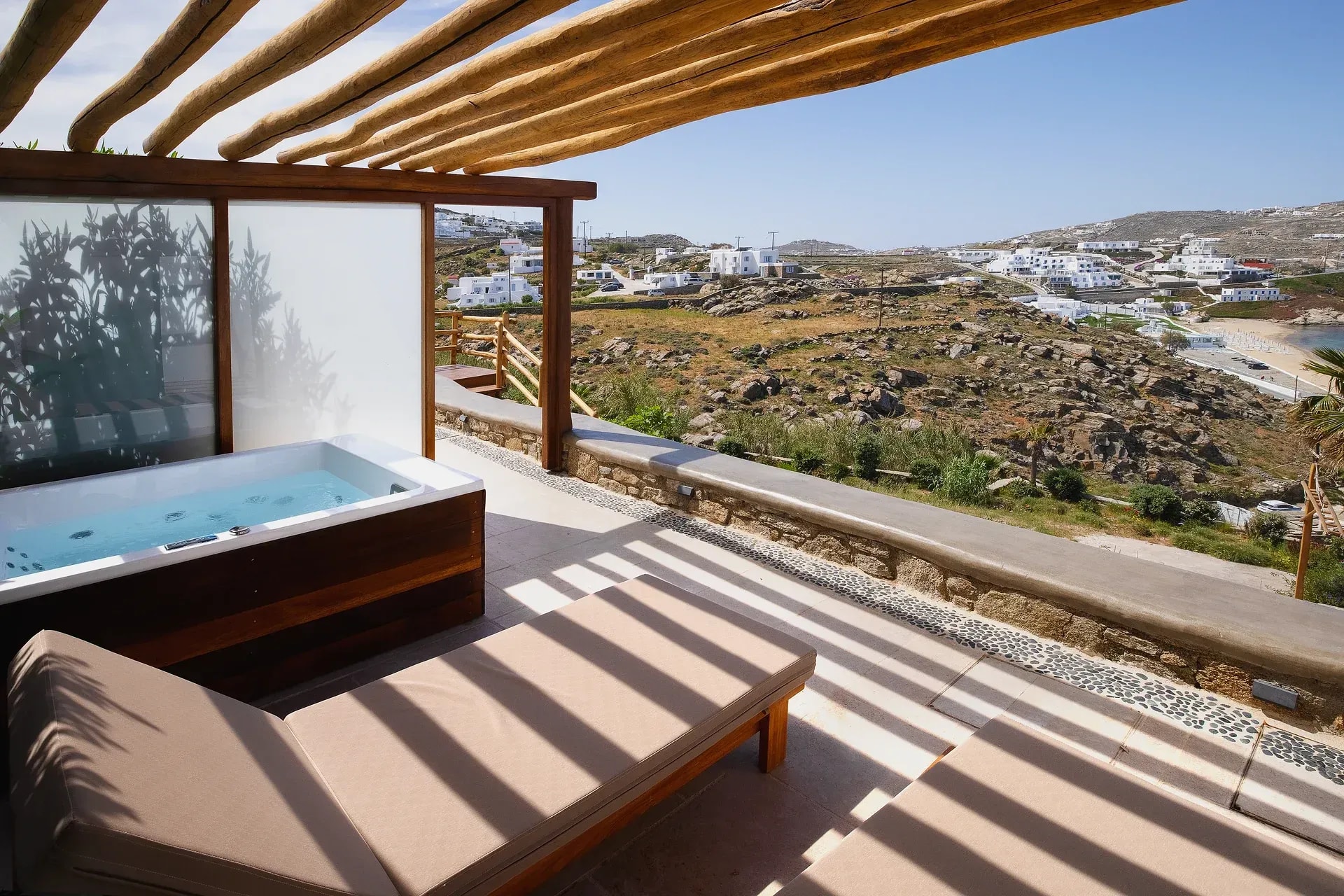 Shaded terrace with seating above the coastline at Legacy Mykonos