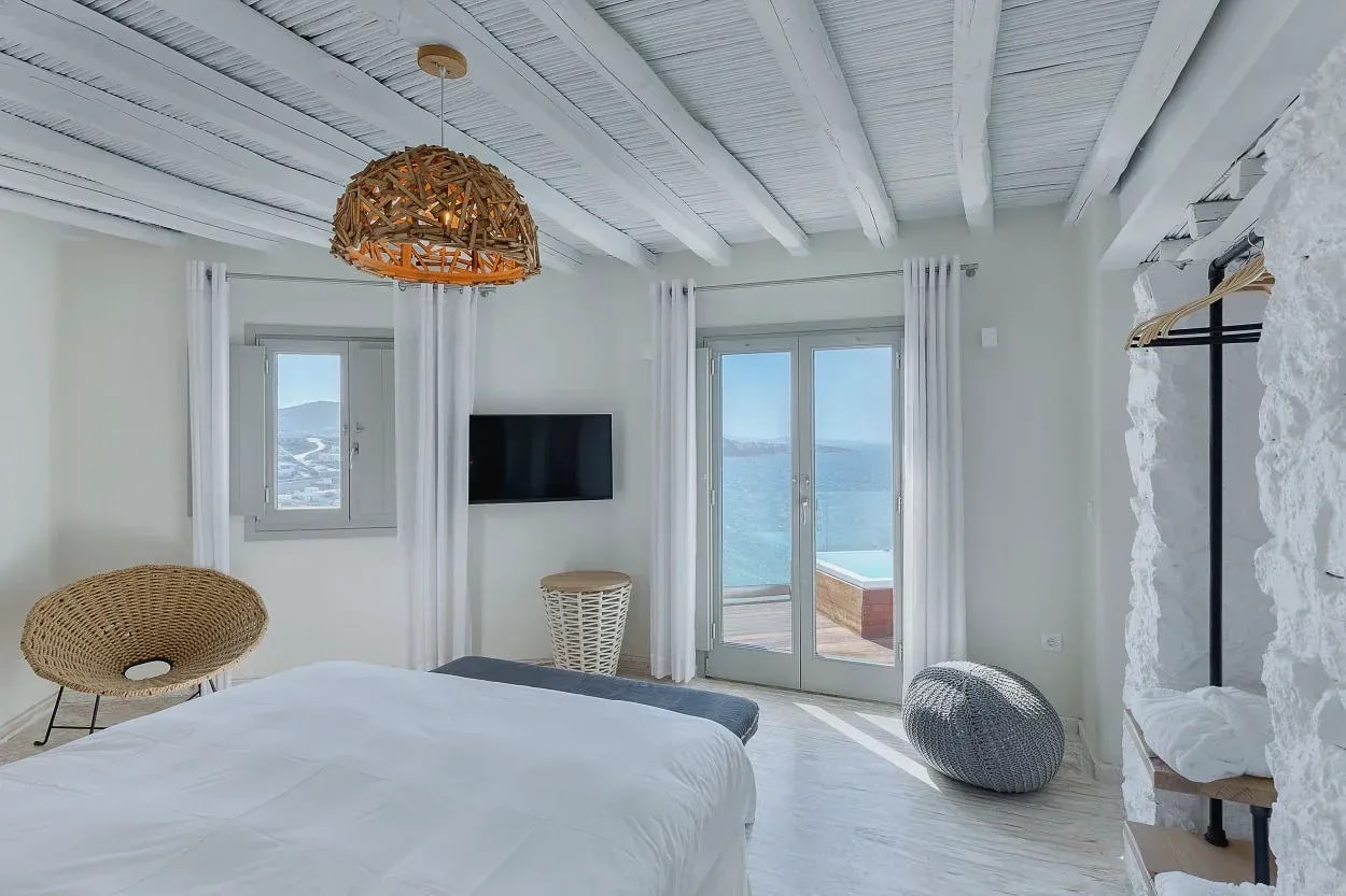 Bedroom with white beam ceiling and French doors onto the terrace