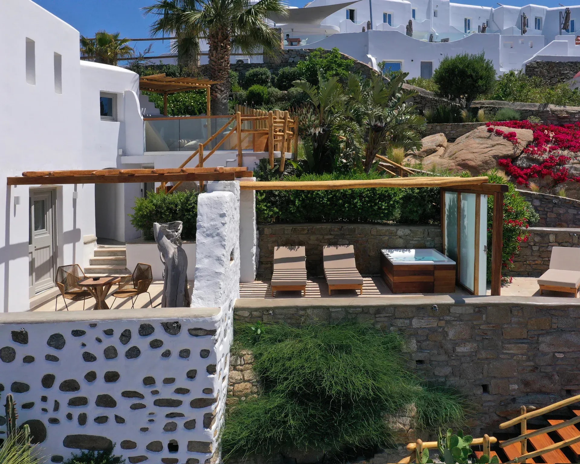 The whitewashed terraces of Legacy Mykonos stepping down between bougainvillea and rock